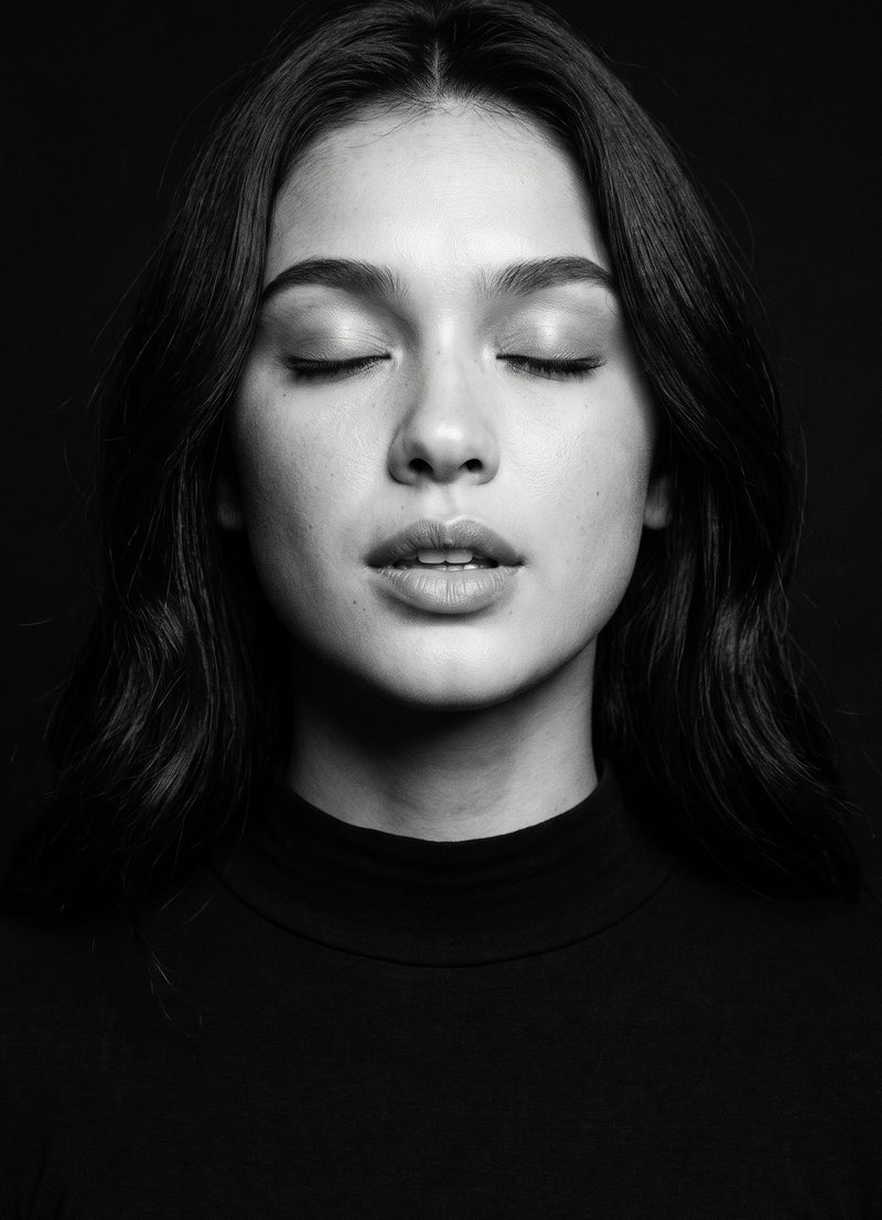Nova Rai with her eyes closed, about to sing, in black and white
