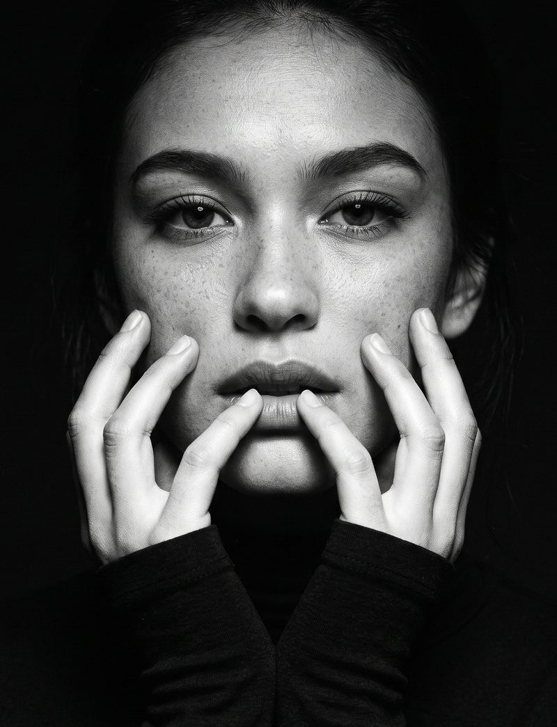 Nova Rai with her hands at her lips, looking into the camera, in black and white