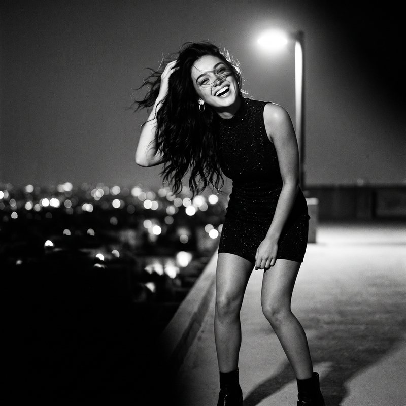 Nova Rai dancing on a rooftop at night, her hair flying, the city lights behind her, in black and white