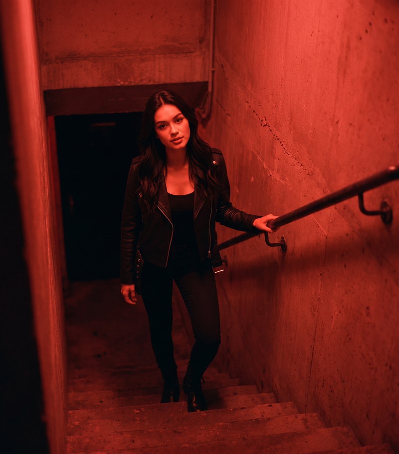 Nova Rai on a red-lit stairwell going down to a club